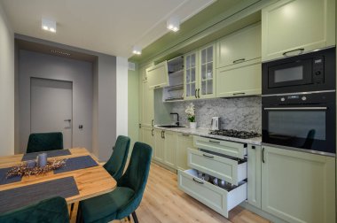 Modern trend açık yeşil lüks mutfak, yemek masası ve koyu yeşil sandalyeler, bazı çekmeceler geri çekilir