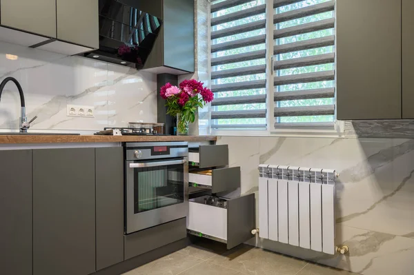 Real showcase interior of small modern trendy gray kitchen, drawrs retracted to show inside