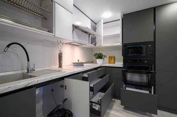 Closeup details of showcase interior of modern simple trendy dark grey and white kitchen, drawers retracted