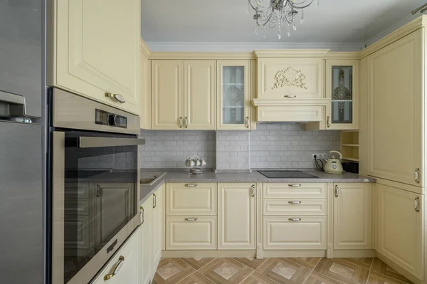 Real showcase interior of modern trendy cream colored kitchen