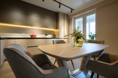 Modern gri lüks mutfak stüdyo dairesinin içinde, yemek masasına yakın.