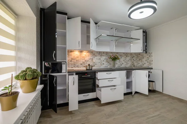 Interior renovation showcase of well designed modern trendy white kitchen, cabinet doors open, drawers retracted