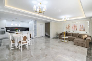 Luxurious large domestic kitchen with marble floor, dining table and sofa