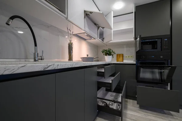 Closeup details of showcase interior of modern simple trendy dark grey and white kitchen, drawers retracted