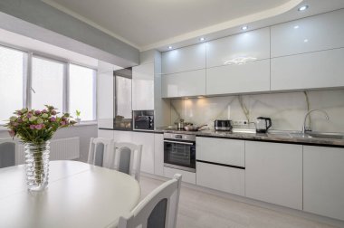 Interior of white trendy modern kitchen with dining table