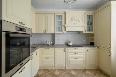 Real showcase interior of modern trendy cream colored kitchen