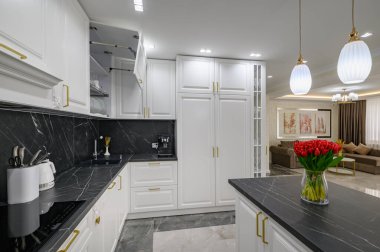 Closeup to black granite worktop of white domestic kitchen with marble floor and kitchen island