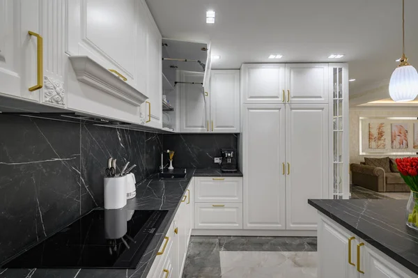 Closeup to black granite worktop of white domestic kitchen with marble floor and kitchen island