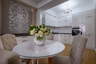 Stüdyo dairede yuvarlak yemek masası olan lüks beyaz modern mutfak.