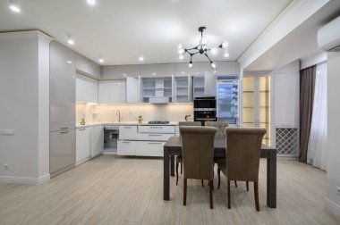 Stüdyo dairenin yenilenmesinden sonra beyaz, yeni, iyi tasarlanmış, pencereleri perdeli beyaz mutfak.