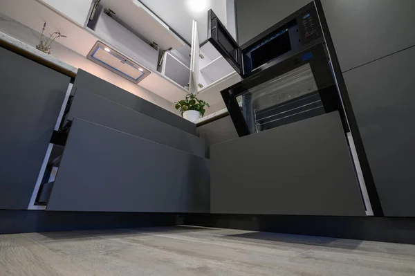 Closeup details of showcase interior of modern simple dark grey and white kitchen, drawers retracted, low angle view