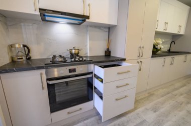 Lüks bej ve krem mutfak iç dekorasyon ayrıntıları, bazı çekmeceler geri çekilmiş, yüksek açılı görünüm