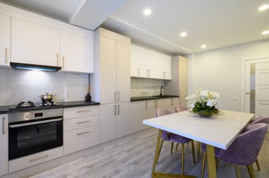 Büyük, lüks bir bej ve krem mutfak ve yemek masası.