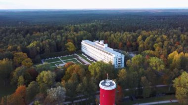 Letonya, Jurmala 'daki Kemeri Resort Parkı' nda Letonya Bayraklı Kemeri Su Kulesi. Arka plandaki güzel Beyaz Neoklasisizm Mimarlık Evi. Yukarıdan hava görüntüsü. Renkli Sonbahar Akşamı