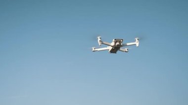 Beyaz İHA Doğada Uçuyor. Uçan Helikopterde İHA asılı. Dron Uzaktan Kumandalı Hava Dronu.