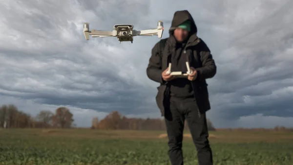 White Drone Flying on Nature Background. Drone Hanging in Air Flying Helicopter Dron  Remote Control Air Drone. Blured Face Pilot With Controler in background