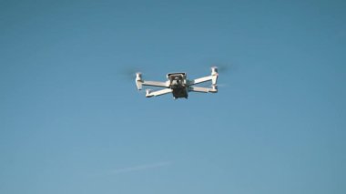 Beyaz İHA Doğada Uçuyor. Uçan Helikopter Dron Uzaktan Kumandalı Hava Dronu 'nda İHA asılı. Yavaş Hareket Görüntüsü.