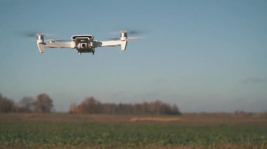 Beyaz İHA Doğada Uçuyor. Uçan Helikopter Dron Uzaktan Kumandalı Hava Dronu 'nda İHA asılı. Yavaş Hareket Görüntüsü.