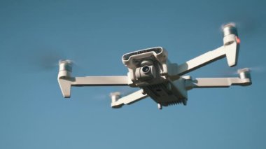 Beyaz İHA Doğada Uçuyor. Uçan Helikopterde İHA asılı. Dron Uzaktan Kumandalı Hava Dronu.