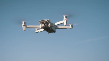 Beyaz İHA Doğada Uçuyor. Uçan Helikopterde İHA asılı. Dron Uzaktan Kumandalı Hava Dronu.