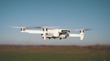 Beyaz İHA Doğada Uçuyor. Uçan Helikopter Dron Uzaktan Kumandalı Hava Dronu 'nda İHA asılı. Yavaş Hareket Görüntüsü.