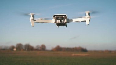 Beyaz İHA Doğada Uçuyor. Uçan Helikopter Dron Uzaktan Kumandalı Hava Dronu 'nda İHA asılı. Yavaş Hareket Görüntüsü.