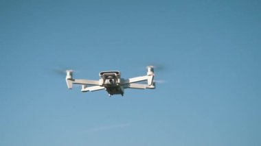 Beyaz İHA Doğada Uçuyor. Uçan Helikopter Dron Uzaktan Kumandalı Hava Dronu 'nda İHA asılı. Yavaş Hareket Görüntüsü.