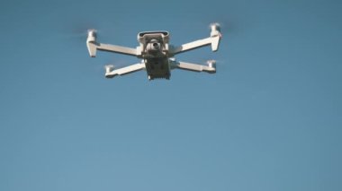 Beyaz İHA Doğada Uçuyor. Uçan Helikopterde İHA asılı. Dron Uzaktan Kumandalı Hava Dronu.