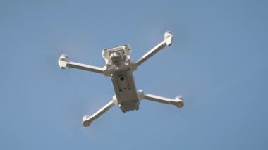 Beyaz İHA Doğada Uçuyor. Uçan Helikopter Dron Uzaktan Kumandalı Hava Dronu 'nda İHA asılı. Yavaş Hareket Görüntüsü.