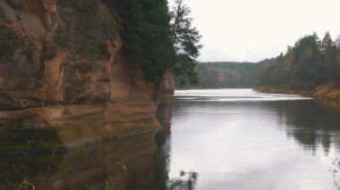 Erglu Kayalıkları ve Gauja Nehri Cesis, Letonya Büyük Manzarası. Gauja Ulusal Parkı 'ndaki Sonbahar Manzarası Kızıl Kayalar Taş Kayalıkları ve Nehir. Stedicam Dolly 4K 'yı vurdu.