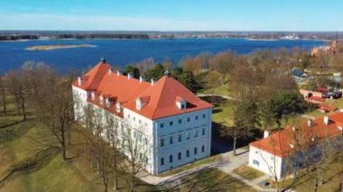 Birzai Kalesinin Hava Çekimi, Birzai Kalesi - Birzai 'de bir kale, Litvanya' daki Irvna Gölü 'nün güney kıyısında, Güneşli Bahar Günü. Tarihi Güzel Kilise ve Birzai Şehri Panoraması 4K UHD Kararı