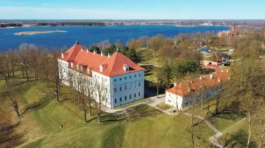 Birzai Kalesinin Hava Çekimi, Birzai Kalesi - Birzai 'de bir kale, Litvanya' daki Irvna Gölü 'nün güney kıyısında, Güneşli Bahar Günü. Tarihi Güzel Kilise ve Birzai Şehri Panoraması 4K UHD Kararı