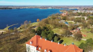 Birzai Kalesinin Hava Çekimi, Birzai Kalesi - Birzai 'de bir kale, Litvanya' daki Irvna Gölü 'nün güney kıyısında, Güneşli Bahar Günü. Tarihi Güzel Kilise ve Birzai Şehri Panoraması 4K UHD Kararı