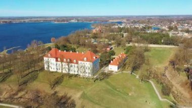 Birzai Kalesinin Hava Çekimi, Birzai Kalesi - Birzai 'de bir kale, Litvanya' daki Irvna Gölü 'nün güney kıyısında, Güneşli Bahar Günü. Tarihi Güzel Kilise ve Birzai Şehri Panoraması 4K UHD Kararı
