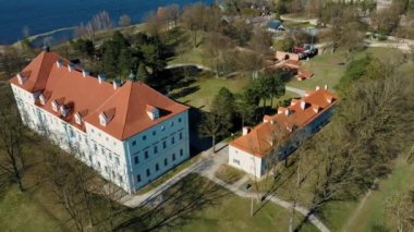 Birzai Kalesinin Hava Çekimi, Birzai Kalesi - Birzai 'de bir kale, Litvanya' daki Irvna Gölü 'nün güney kıyısında, Güneşli Bahar Günü. Tarihi Güzel Kilise ve Birzai Şehri Panoraması 4K UHD Kararı