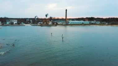 Baltık Denizi 'ndeki Engure Limanı' nda bir Corekites Kitesurfers Hidrofoiling 'in hava aracı görüntüsü. Günbatımında Kiter Biniciliğinin 4K Drone Görüntüsü. 