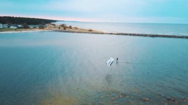 Baltık Denizi 'ndeki Engure Limanı' nda bir Corekites Kitesurfers Hidrofoiling 'in hava aracı görüntüsü. Günbatımında Kiter Biniciliğinin 4K Drone Görüntüsü. 
