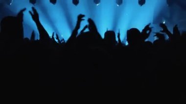 Tanınmayan Hayranlar Bir Konser veya Festival Partisinde Dans Etmek ve Ellerini Kaldırmak. Seyircilerin Siluetleri Parlak Sahne Işıklarının Önündeki Konserin tadını çıkarıyor.