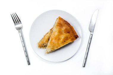 Tabakta ustenil ile servis edilen etli Burek geleneksel turtası. Geleneksel Balkan kahvaltısı. Beyaz arka planda izole edilmiş. Üst Görünüm