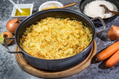 İçinde pirinç, soğan, havuç, baharat ve zeytinyağı bulunan büyük bir tavada İtalyan vejetaryen risotto.