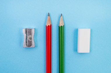 Mavi arka planda iki kalem açacağı ve silgi. Üst Manzara. Okul kavramı