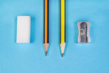 Mavi arka planda iki kalem açacağı ve silgi. Üst Manzara. Okul kavramı