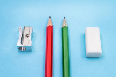 Mavi arka planda iki kalem açacağı ve silgi. Üst Manzara. Okul kavramı