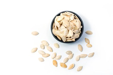 Beyaz arka planda izole edilmiş kabak tohumları ve etrafa saçılan tohumlar. Atıştırmalıklar için kavrulmuş ve tuzlanmış kabak çekirdekleri - üst görünüm