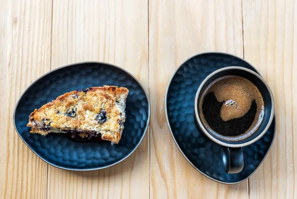 自家製のおいしいスライスしたアップルブルーベリーパイ黒いサービングプレートと木製のテーブルの上に黒いコーヒーカップ トップ表示 — ストック写真