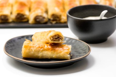 Köfteler hamur işi yapar. Siyah oval tabakta yumurta rulolarında kızarmış domuz eti. Beyaz arka planda izole edilmiş, rulo rulo rulo rulo şeklinde. Seçici odak.