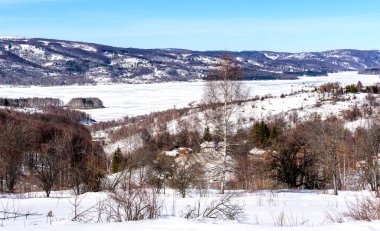 Arka planda tepeler olan donmuş göl manzarası. Soğuk bir kış gününde Donmuş Göl