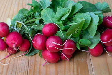 Bir demet kırmızı turp. Taze hasat edilmiş, ahşap bir masada mor renkli turp.