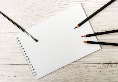 Beyaz tahta zemin üzerine çizim yapmak için beyaz çarşaflı ve renkli kalemli defter