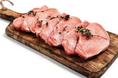 Beyaz arka planda tahta üzerinde çiğ domuz eti ve kuru fesleğen yaprağı ve baharat. Beyaza izole edilmiş taze çiğ sığır eti. Bir yığın çiğ biftek.